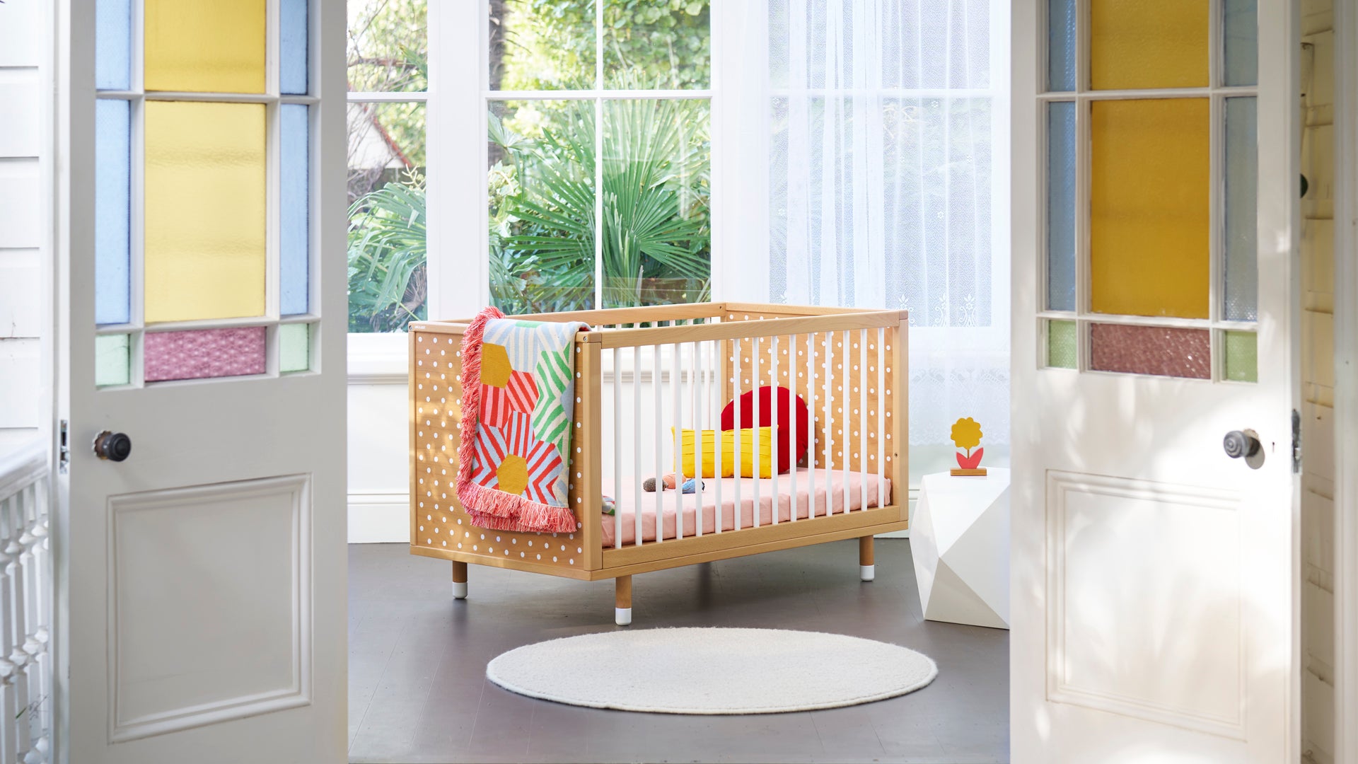 Beechwood cot with white dots on it in a stylish room