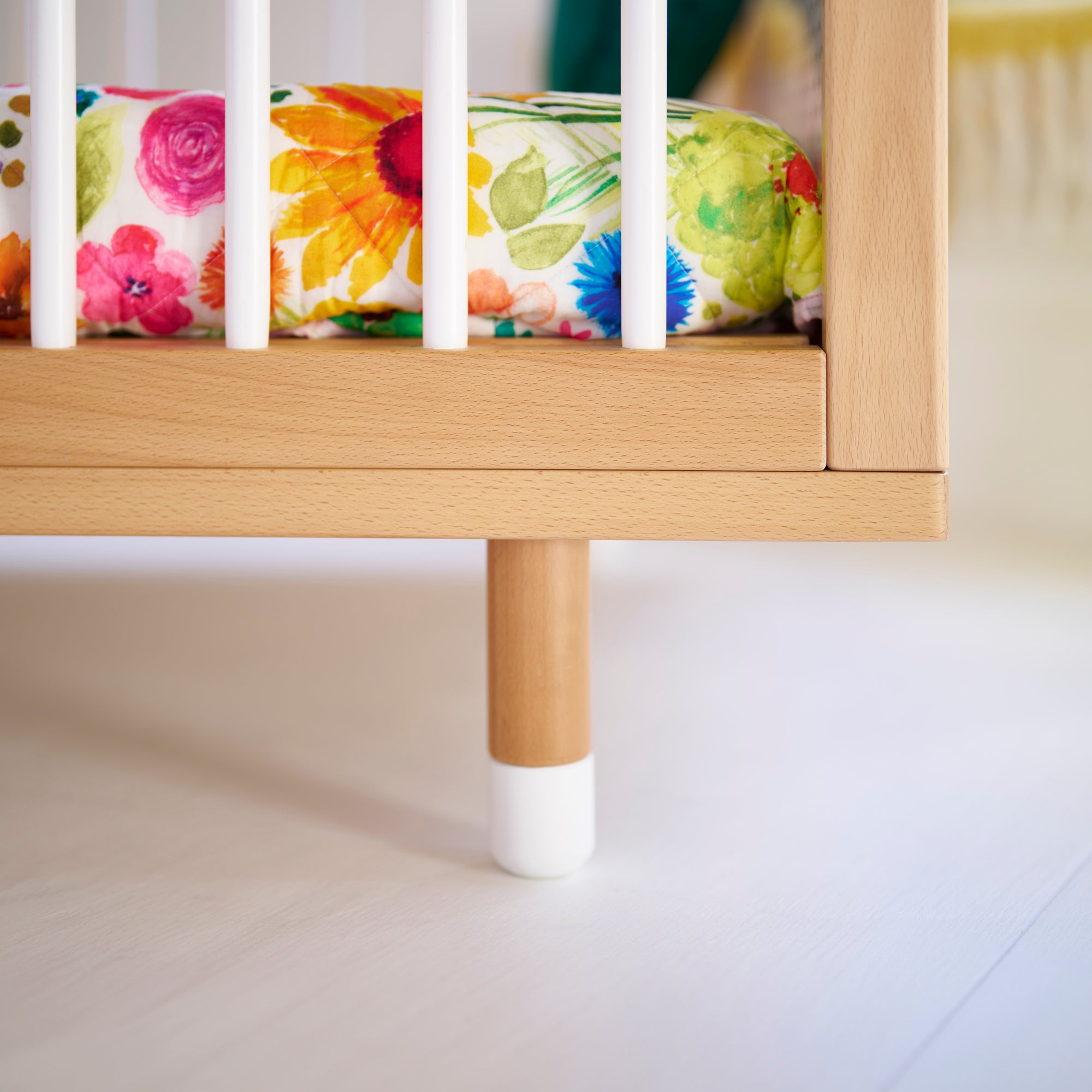 A close up of a leg of a cot with a white painted end