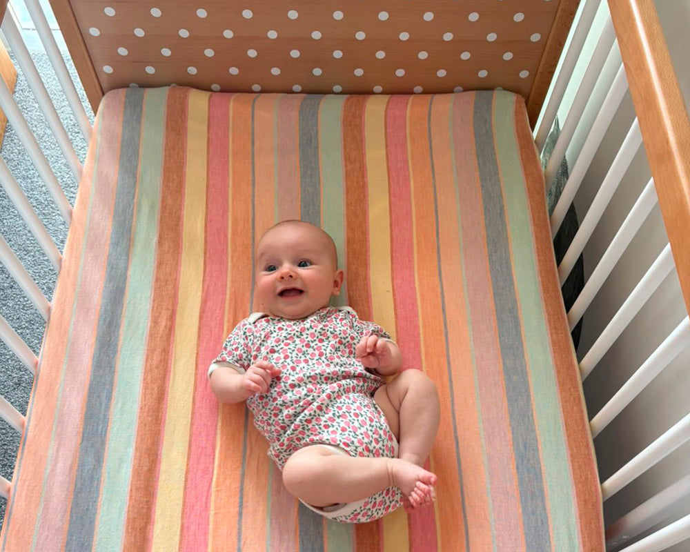 Overhead view of smiling baby in a cot