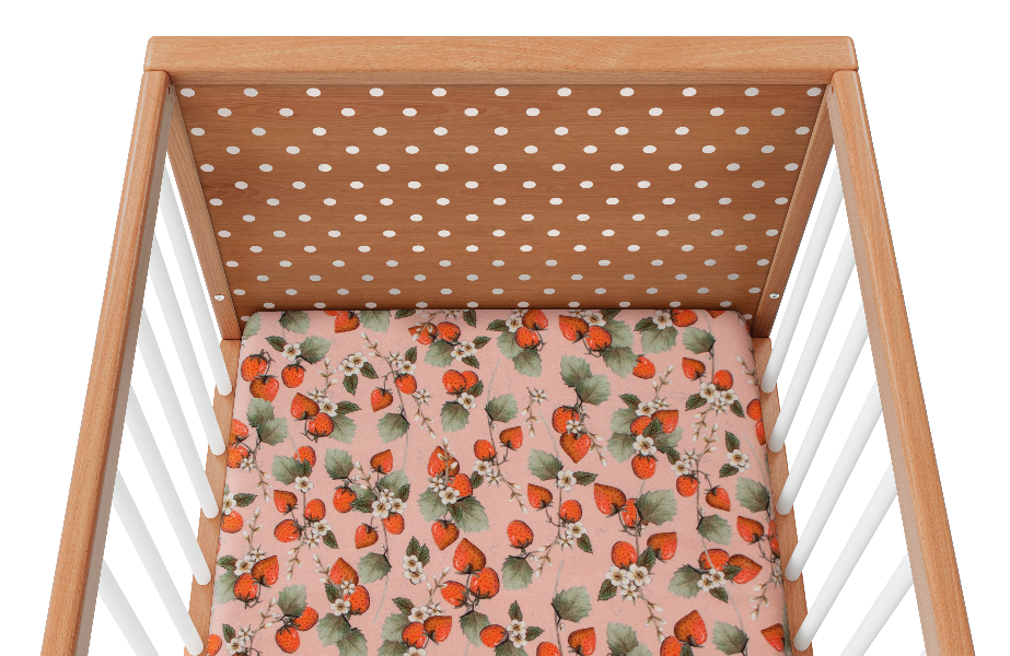 Overhead view of a wooden cot with strawberry sheet